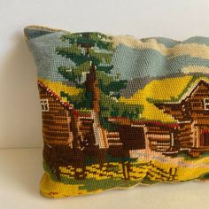 a decorative pillow with a cabin scene on it's front and back sides, sitting on a white surface