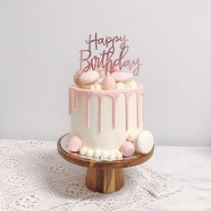 a birthday cake with pink frosting and sprinkles on a wooden stand