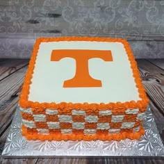 a cake with the letter t on it is sitting on top of a wooden table