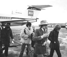 some people are walking towards an airplane on the tarmac and one is wearing a fur coat