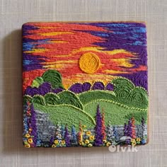 a small patchwork wallet with an image of the sun setting over mountains and trees