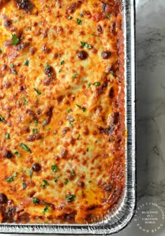 a cheesy casserole in a metal pan on a marble countertop