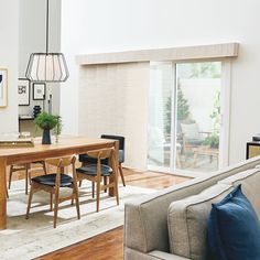 a living room and dining area with wood flooring, white walls and wooden furniture