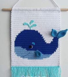 a crocheted wall hanging with a blue whale on it