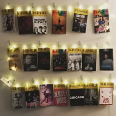 there are many books on the wall with lights around them and some posters hanging up against the wall