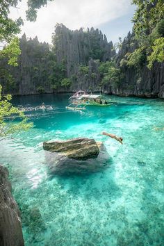 the water is crystal blue and clear with rocks on both sides, surrounded by green trees