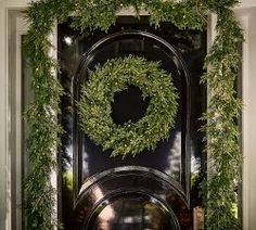 the door is decorated with greenery and a wreath on it's front entrance