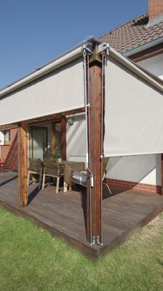 an image of a house with awnings on the deck and table in front