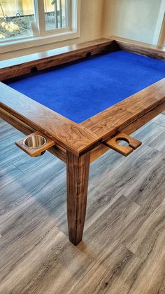 a pool table with a blue cloth on it and two bowls in the bottom drawer