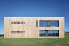 a large wooden building sitting on top of a lush green field with lots of windows