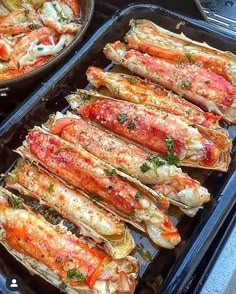 two pans filled with cooked lobster on top of a stove next to each other