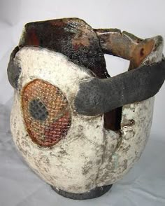 a close up of a vase on a white surface with a black handle and an orange face