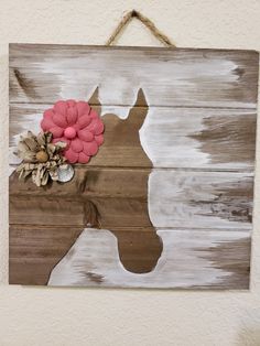 a wooden sign with a horse painted on it's side and flowers in the center