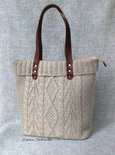 a knitted tote bag with brown leather handles on a gray cloth back ground