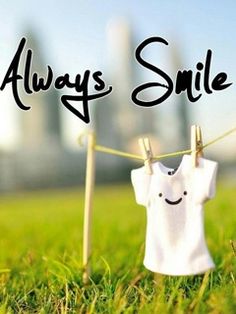 a white shirt hanging on a clothes line with the words always smile written above it