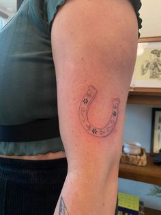 a woman's arm with a horseshoe tattoo on it