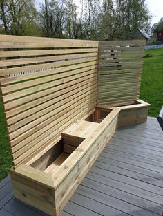 a wooden bench sitting on top of a wooden deck next to a green grass covered field