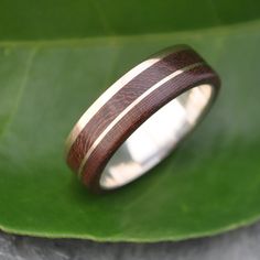 a wooden ring sitting on top of a green leaf