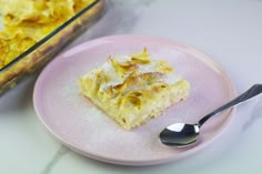 a pink plate topped with a piece of cake next to a casserole dish