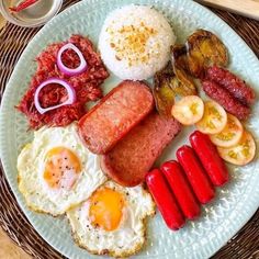 a white plate topped with eggs, sausage and other foods