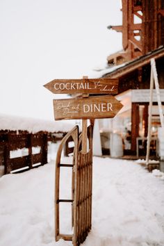 two wooden signs pointing to different locations in the snow