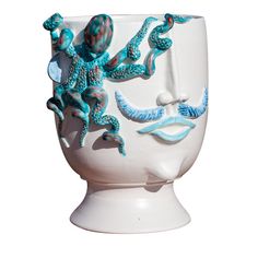 a white vase with blue and red designs on the outside, sitting in front of a white background