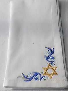 a white shirt with blue and gold designs on the front, along with a star of david embroidered on the back