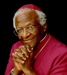 an older man wearing glasses and a red jacket with his hands folded on his chest