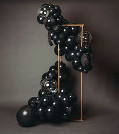 a bunch of black balloons sitting on top of a metal stand