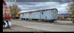 an old train car sitting on the tracks next to a red and yellow train caboose