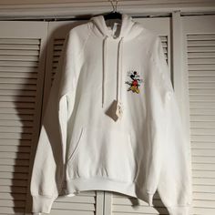 White Sweatshirt With Small Design On Front And Large On Back. 23.5 Inches Across The Chest. Care Tag Pictured. Kangaroo Pocket And Hood. Strain From Factory Or Store. White Disney Cartoon Print Sweatshirt, Cotton Hoodie With Mickey Mouse Design, Cotton Mickey Mouse Hooded Top, Mickey Mouse Cotton Hooded Top, Disney Mickey Mouse Long Sleeve Hoodie, Mickey Mouse Sweatshirt, Disney Tops, White Sweatshirt, Small Designs