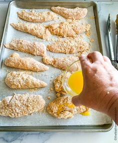 a person is dipping something into a glass on a baking sheet with other food items and utensils