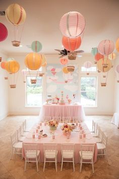 a dining room filled with lots of tables covered in pink and yellow paper lantern decorations