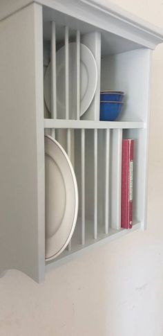 an open shelf with plates and books on it