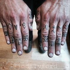 two hands with tattoos on them, one has an arrow and the other has letters