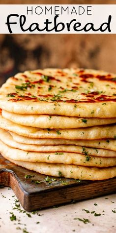 a stack of pita bread sitting on top of a wooden cutting board