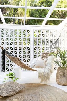 a hammock hanging from the ceiling in front of a white fence