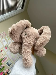 an elephant stuffed animal sitting on top of a towel in front of a window sill