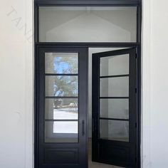 an open black double door in front of a white building with glass panels on the doors