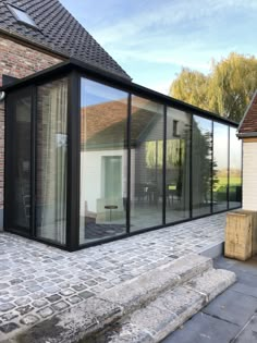 a house that has some glass walls on the side of it and brick steps leading up to it