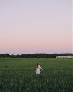 a woman in a white dress walking through a field