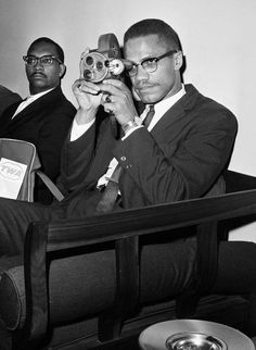 three men in suits and ties are taking pictures with their cameras while sitting on a chair