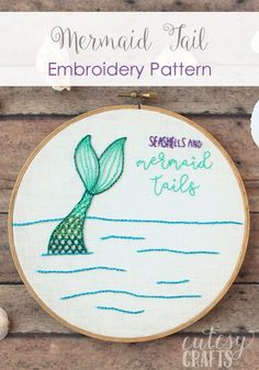 the mermaid tail embroidery pattern is shown on a wooden table with shells and seashells