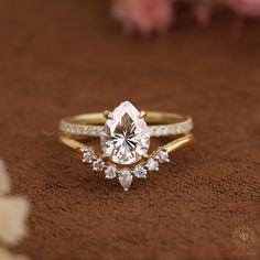 a close up of a diamond ring on a brown surface with flowers in the background