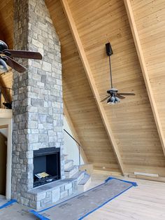 a living room with a stone fireplace and ceiling fan in the middle of the room