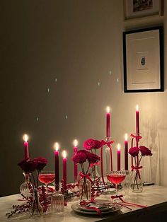 a table topped with lots of candles next to wine glasses and plates filled with flowers