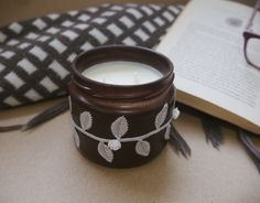 a candle sitting on top of a table next to an open book and eyeglasses