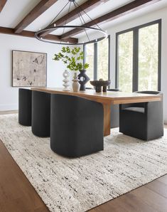 a dining room table with four chairs and a rug in front of the window that overlooks trees