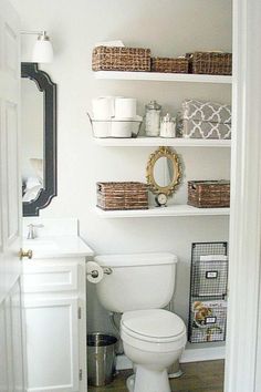 a white toilet sitting in a bathroom next to a sink and shelves with baskets on it