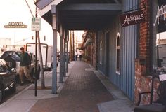 a man walking down the sidewalk next to parked cars